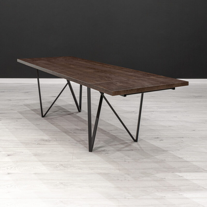 Stół Ravel z dostawkami wykonany z litego drewna dębowego pokrytego bejcą i metalu.
